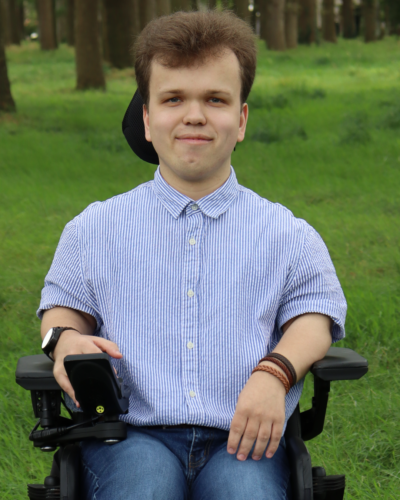 Tim Paul Ploeger, kandidaat nummer 2 uit Vries (Gemeente Tynaarlo). Tim Paul zit in zijn rolstoel, welke op gras staat